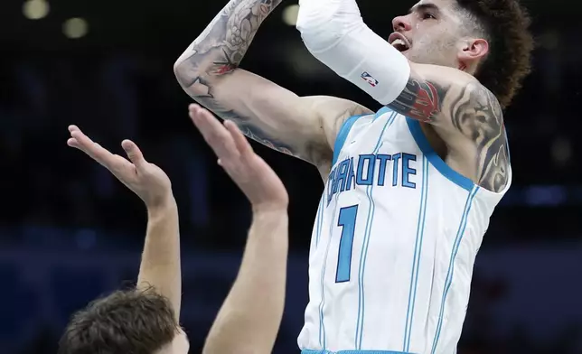 Charlotte Hornets guard LaMelo Ball, right, shoots against Miami Heat guard Pelle Larsson during the first half of an NBA basketball game in Charlotte, N.C., Wednesday, Nov. 27, 2024. (AP Photo/Nell Redmond)