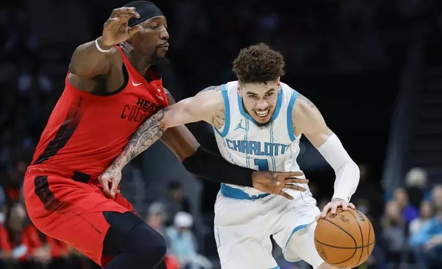 Charlotte Hornets guard LaMelo Ball, right, drives against Miami Heat center Bam Adebayo during the first half of an NBA basketball game in Charlotte, N.C., Wednesday, Nov. 27, 2024. (AP Photo/Nell Redmond)