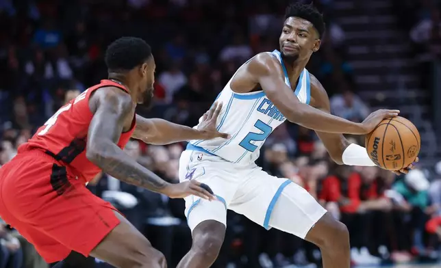 Charlotte Hornets forward Brandon Miller, right, looks to pass against Miami Heat forward Haywood Highsmith during the first half of an NBA basketball game in Charlotte, N.C., Wednesday, Nov. 27, 2024. (AP Photo/Nell Redmond)