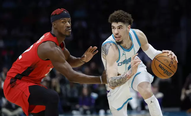 Charlotte Hornets guard LaMelo Ball, right, drives against Miami Heat forward Jimmy Butler during the first half of an NBA basketball game in Charlotte, N.C., Wednesday, Nov. 27, 2024. (AP Photo/Nell Redmond)