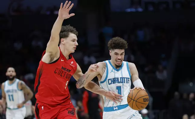 Charlotte Hornets guard LaMelo Ball, right, drives against Miami Heat guard Pelle Larsson during the first half of an NBA basketball game in Charlotte, N.C., Wednesday, Nov. 27, 2024. (AP Photo/Nell Redmond)