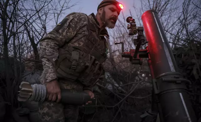 In this photo provided by Ukraine's 24th Mechanised Brigade press service, serviceman of the 24th Mechanised Brigade prepares to fire 120mm mortar towards Russian positions near Chasiv Yar town, in Donetsk region, Ukraine, Tuesday, Nov. 19, 2024. (Oleg Petrasiuk/Ukrainian 24th Mechanised Brigade via AP)