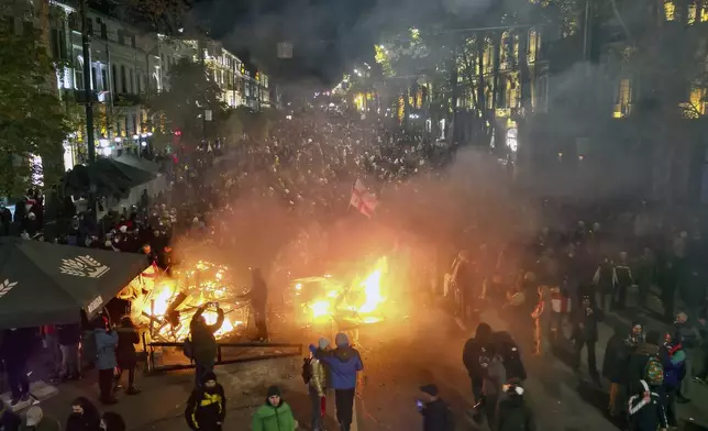 Protesters pour into the streets and put fire following Georgian Prime Minister Irakli Kobakhidze's announcement, rallying outside the parliament building in Tbilisi, Georgia, on Friday, Nov. 29, 2024. (AP Photo/Zurab Tsertsvadze)