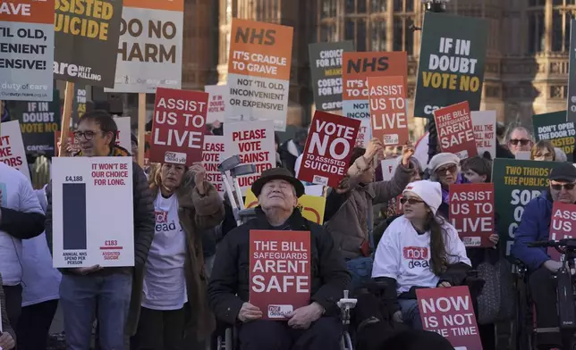 Protesters show placards in front of Parliament in London, Friday, Nov. 29, 2024 as British lawmakers have given initial approval to a bill that would help terminally ill adults to end their lives in England and Wales.(AP Photo/Alberto Pezzali)