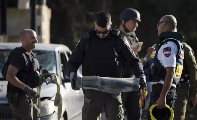 A member of the Israeli security forces carries a piece of a projectile extracted from the site where a rocket, fired from Lebanon, hit an area in the town of Nahariya, northern Israel, Thursday, Nov. 21, 2024. (AP Photo/Leo Correa)