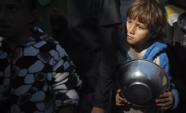 Palestinian children queue at a food distribution kitchen in Deir al-Balah, Gaza Strip, Friday Nov. 22, 2024. (AP Photo/Abdel Kareem Hana)