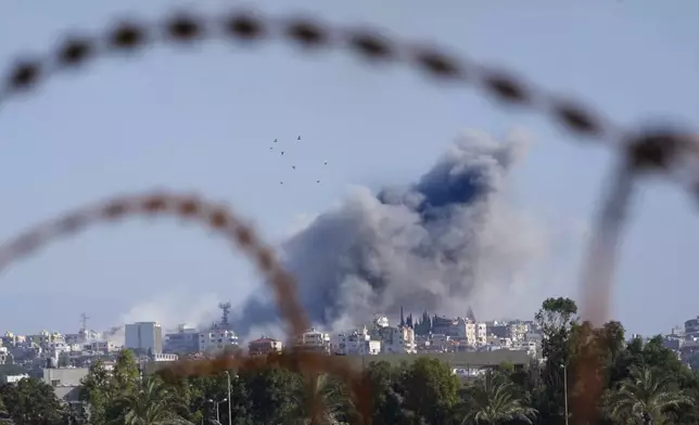 Smoke rises between buildings hit in an Israeli airstrike in Burj al-Shamali village, as it is seen from Tyre city, south Lebanon, Friday, Nov. 22, 2024. (AP Photo/Hussein Malla)