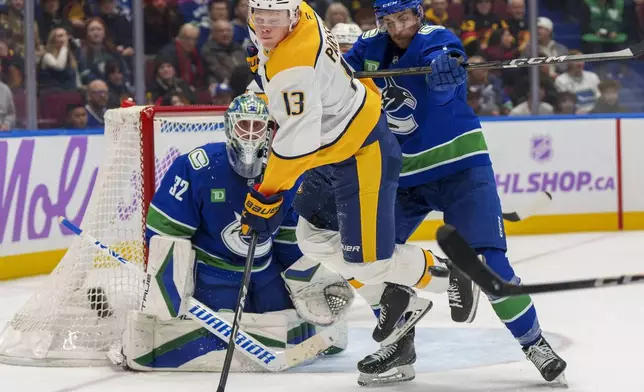 Nashville Predators' Juuso Parssinen (13) gets hit from behind by Vancouver Canucks' Carson Soucy (7) during second period of an NHL hockey match in Vancouver, on Sunday, Nov. 17, 2024. (Christopher Morris/The Canadian Press via AP)