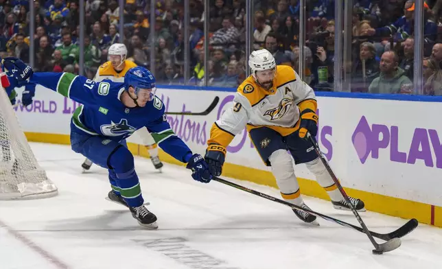 Vancouver Canucks' Tyler Myers (57) pursues Nashville Predators' Filip Forsberg (9) during first period of an NHL hockey match in Vancouver, on Sunday, Nov. 17, 2024. (Christopher Morris/The Canadian Press via AP)