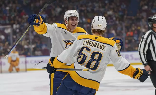 Nashville Predators' Brady Skjei (76) congratulates Nashville Predators' Zachary L'Heureux (68) on his goal during first period NHL hockey against Vancouver Canucks in Vancouver, on Sunday, Nov. 17, 2024. (Christopher Morris/The Canadian Press via AP)