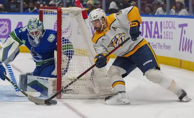 Nashville Predators' Filip Forsberg (9) tries to jam the puck past Vancouver Canucks goalie Kevin Lankinen (32) during first period of an NHL hockey match in Vancouver, on Sunday, Nov. 17, 2024. (Christopher Morris/The Canadian Press via AP)