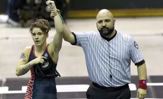 FILE - A referee raises the arm of Mack Beggs of Euless Trinity after he defeated Chelsea Sanchez of Morton Ranch to defend the Class 6A girls 110-pound title during the UIL State Wrestling Championships at the Berry Center in Cypress, Texas, on Saturday, Feb. 24, 2018. Texas limits transgender athletes to teams conforming with the gender on their birth certificate. That law came under criticism in 2017 and 2018, when transgender male Beggs won state titles in girls' wrestling competitions after he was told he could not compete as a boy. (Jason Fochtman/Houston Chronicle via AP)