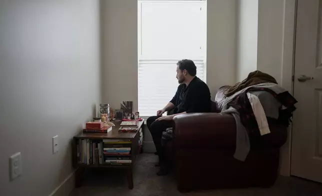 FILE - Ashton Colby looks out the window of his meditation corner in his apartment in Columbus, Ohio, on Thursday, Jan. 18, 2024. Ohio Gov. Mike DeWine announced proposals in January that transgender advocates say could block access to gender-affirming care provided by independent clinics and general practitioners, leaving thousands of adults scrambling for treatment and facing health risks. Colby, 31, fears the clinic where he gets the testosterone he has taken since age 19 would no longer offer it. (AP Photo/Carolyn Kaster, File)