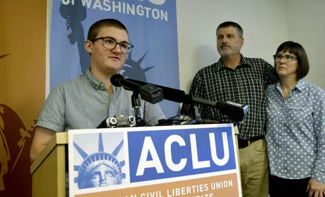 FILE - Paxton Enstad, left, speaks during a news conference about a lawsuit filed over refusal by an insurance plan to cover his gender-reassignment surgery, accompanied by his parents, Cheryl and Mark Enstad, Thursday, Oct. 5, 2017, in Seattle. (AP Photo/Elaine Thompson, File)