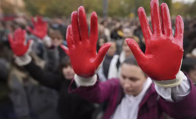 Protesters shout slogans with red paint on the hands symbolizing blood, demand arrests, two days after a concrete canopy collapsed at a railway station in Novi Sad, killing 14 people and injuring three, during protest in Belgrade, Serbia, Sunday, Nov. 3, 2024. (AP Photo/Darko Vojinovic)