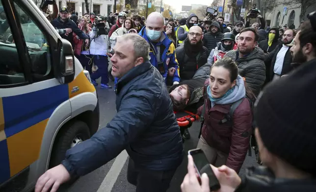 Demonstrators and paramedics carry a wounded person to an ambulance after clashes with police during a rally against the results of the parliamentary elections amid allegations that the vote was rigged in Tbilisi, Georgia, on Tuesday, Nov. 19, 2024. (AP Photo/Zurab Tsertsvadze)