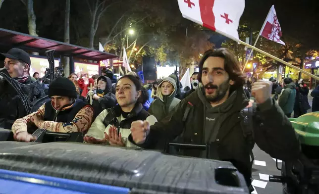 Protesters standing behind a barricade shout in a street during a rally against the results of the parliamentary elections amid allegations that the vote was rigged in Tbilisi, Georgia Tuesday, Nov. 19, 2024. (AP Photo/Zurab Tsertsvadze)