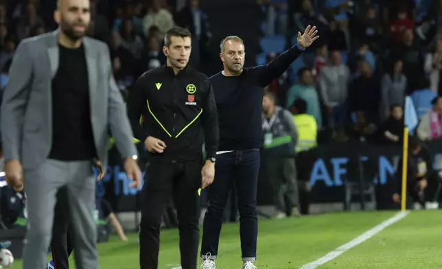 Barcelona's head coach Hansi Flick, back, gestures during the Spanish La Liga soccer match between Celta Vigo and Barcelona at the Balaidos stadium in Vigo, Spain, Saturday, Nov. 23, 2024. (AP Photo/Lalo R. Villar)