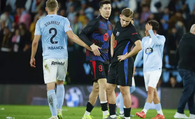 Celta's Carl Starfelt, left, greets Barcelona's Robert Lewandowski, center, past Fermin Lopez after the Spanish La Liga soccer match between Celta Vigo and Barcelona at the Balaidos stadium in Vigo, Spain, Saturday, Nov. 23, 2024. (AP Photo/Lalo R. Villar)