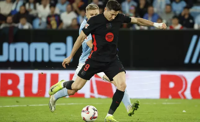 Barcelona's Robert Lewandowski scores his side's 2nd goal challenged by Celta's Carl Starfelt during the Spanish La Liga soccer match between Celta Vigo and Barcelona at the Balaidos stadium in Vigo, Spain, Saturday, Nov. 23, 2024. (AP Photo/Lalo R. Villar)