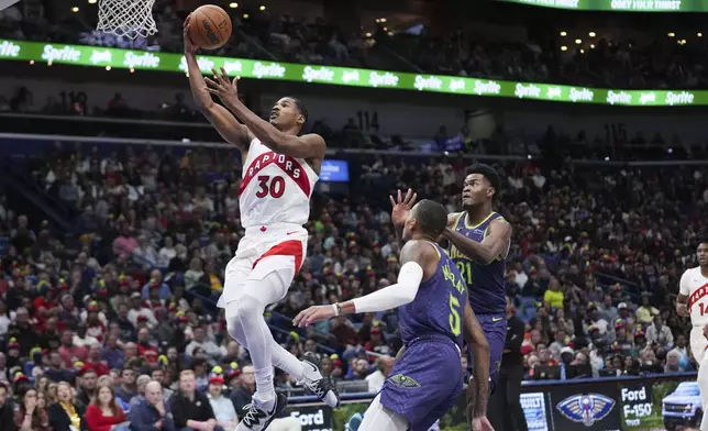 Toronto Raptors guard Ochai Agbaji (30) goes to the basket ahead of New Orleans Pelicans center Yves Missi (21) and guard Dejounte Murray (5) in the first half of an NBA basketball game in New Orleans, Wednesday, Nov. 27, 2024. (AP Photo/Gerald Herbert)