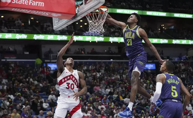 New Orleans Pelicans center Yves Missi (21) tries to block a shot by Toronto Raptors guard Ochai Agbaji (30) in the first half of an NBA basketball game in New Orleans, Wednesday, Nov. 27, 2024. (AP Photo/Gerald Herbert)