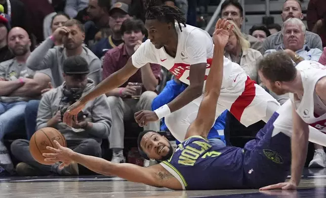 New Orleans Pelicans guard CJ McCollum (3) falls for a loose ball against Toronto Raptors guard Ja'Kobe Walter in the first half of an NBA basketball game in New Orleans, Wednesday, Nov. 27, 2024. (AP Photo/Gerald Herbert)