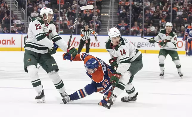 Minnesota Wild's Jonas Brodin (25) and Joel Eriksson Ek (14) check Edmonton Oilers' Connor McDavid (97) during second-period NHL hockey game action in Edmonton, Alberta, Thursday, Nov. 21, 2024. (Jason Franson/The Canadian Press via AP)