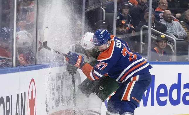 Minnesota Wild's Jakub Lauko (94) is checked by Edmonton Oilers' Brett Kulak (27) during third-period NHL hockey game action in Edmonton, Alberta, Thursday, Nov. 21, 2024. (Jason Franson/The Canadian Press via AP)