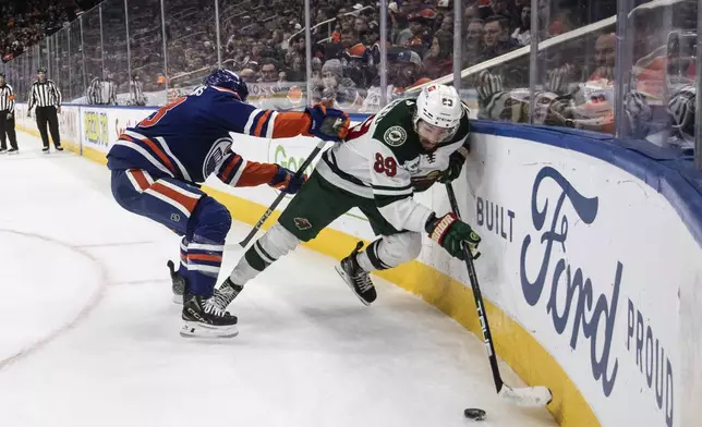 Minnesota Wild's Frederick Gaudreau (89) is checked by Edmonton Oilers' Ryan Nugent-Hopkins (93) during third period NHL action in Edmonton on Thursday, Nov. 21, 2024. (Jason Franson/The Canadian Press via AP)