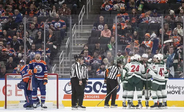 Minnesota Wild players, right, celebrate after a goal as Edmonton Oilers goalie Stuart Skinner (74) and Mattias Ekholm (14) react during second-period NHL hockey game action in Edmonton, Alberta, Thursday, Nov. 21, 2024. (Jason Franson/The Canadian Press via AP)