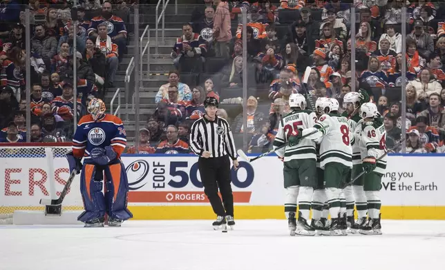 Minnesota Wild players, right, celebrate after a goal as Edmonton Oilers goalie Stuart Skinner (74) looks on during second-period NHL hockey game action in Edmonton, Alberta, Thursday, Nov. 21, 2024. (Jason Franson/The Canadian Press via AP)