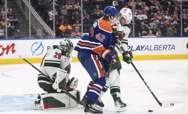 Minnesota Wild goalie Marc-Andre Fleury (29) makes a save as Edmonton Oilers' Kasperi Kapanen (42) and Jonas Brodin (25) battle for a rebound during second-period NHL hockey game action in Edmonton, Alberta, Thursday, Nov. 21, 2024. (Jason Franson/The Canadian Press via AP)