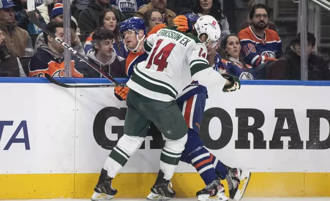 Minnesota Wild's Joel Eriksson Ek (14) checks Edmonton Oilers' Corey Perry, back, during second-period NHL hockey game action in Edmonton, Alberta, Thursday, Nov. 21, 2024. (Jason Franson/The Canadian Press via AP)