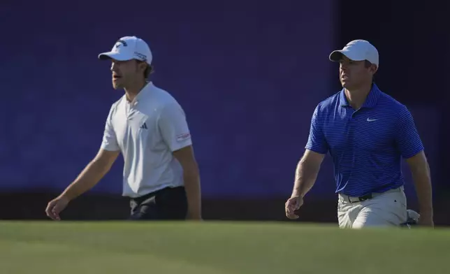 Rasmus Højgaard of Denmark, left, and Rory McIlroy of Northern Ireland walk towards 17th green in the final round of World Tour Golf Championship in Dubai, United Arab Emirates, Sunday, Nov. 17, 2024. (AP Photo/Altaf Qadri)