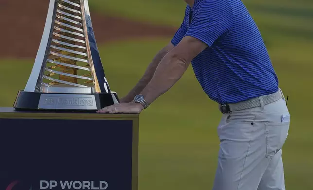 Rory McIlroy of Northern Ireland stands next Race to Dubai trophy during the award ceremony after winning the World Tour Golf Championship in Dubai, United Arab Emirates, Sunday, Nov. 17, 2024. (AP Photo/Altaf Qadri)