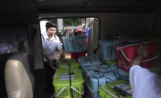 Let's Adopt Indonesia volunteers Ian Gunawan, left, and Vanya Afreenzha put baskets containing stray cats into a van during a "Trap, Neuter and Return" project aimed at reducing stray cat population, in Jakarta, Indonesia, on Nov. 9, 2024. (AP Photo/Dita Alangkara)