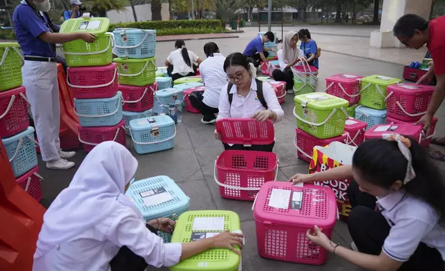 Volunteers prepare plastic containers to be used to transport cats during a "Trap, Neuter and Return" project aimed at reducing stray cat population, in Jakarta, Indonesia, on Nov. 9, 2024. (AP Photo/Dita Alangkara)