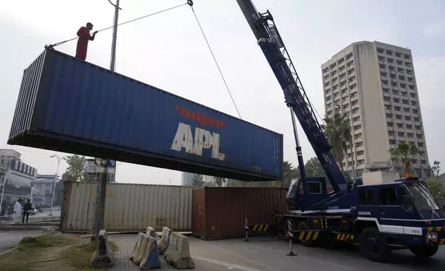 Workers place shipping containers to close a road ahead of a planned rally by supporters of imprisoned former Prime Minister Imran Khan's Pakistan Tehreek-e-Insaf party, in Islamabad, Pakistan, Saturday, Nov. 23, 2024. (AP Photo/Anjum Naveed)