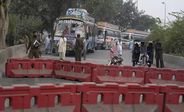 Police officers stand guard on an entry point to motorway leading to Islamabad, which has been closed by authorities due to a planned rally by supporters of imprisoned former Prime Minister Imran Khan's Pakistan Tehreek-e-Insaf party, in Lahore, Pakistan, Saturday, Nov. 23, 2024. (AP Photo/K.M. Chaudary)