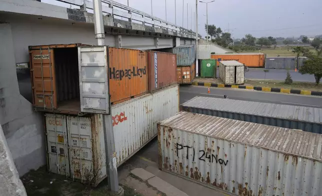 Motorcyclists drive on a highway, which partially closed with shipping containers ahead of a planned rally by supporters of imprisoned former Prime Minister Imran Khan's Pakistan Tehreek-e-Insaf party, in Islamabad, Pakistan, Saturday, Nov. 23, 2024. (AP Photo/Anjum Naveed)