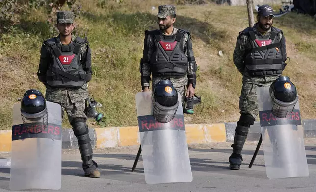 Paramilitary soldiers stand guard with riot gears at a road barricaded with shipping containers ahead of a planned rally by supporters of imprisoned former Prime Minister Imran Khan's Pakistan Tehreek-e-Insaf party, in Islamabad, Pakistan, Sunday, Nov. 24, 2024. (AP Photo/Anjum Naveed)