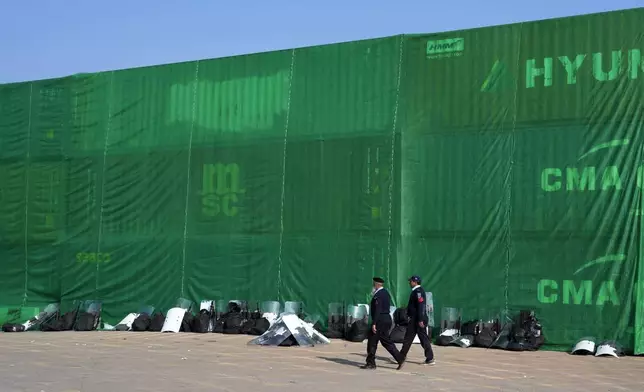 Police officers patrol at a road barricaded with shipping containers ahead of a planned rally by supporters of imprisoned former Prime Minister Imran Khan's Pakistan Tehreek-e-Insaf party, in Islamabad, Pakistan, Sunday, Nov. 24, 2024. (AP Photo/Anjum Naveed)