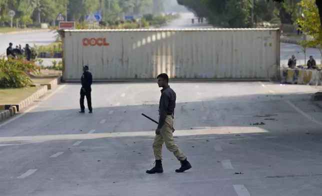 Police officers patrol at a road barricaded with shipping containers ahead of a planned rally by supporters of imprisoned former Prime Minister Imran Khan's Pakistan Tehreek-e-Insaf party, in Islamabad, Pakistan, Sunday, Nov. 24, 2024. (AP Photo/Anjum Naveed)