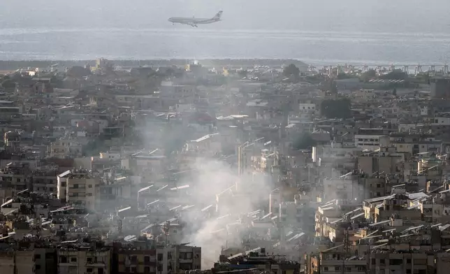 A Middle East Airlines airplane flies over Dahiyeh as smoke rises from Israeli an airstrike, in the southern suburb of Beirut, Lebanon, Saturday, Nov. 16, 2024. (AP Photo/Bilal Hussein)