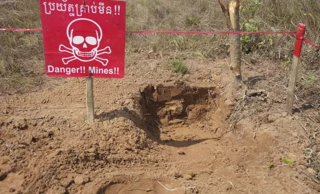 A "Danger Mine" sign marks an area as Cambodia Mine Action Center, CMAC, staff members work at a minefield in Preytotoeung village, Battambang province, Cambodia, Thursday, Jan. 19, 2023. (AP Photo/Heng Sinith)