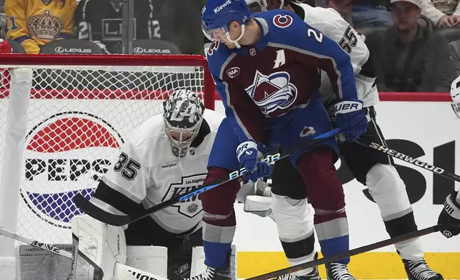 Colorado Avalanche center Nathan MacKinnon, front, redirects a shot past Los Angeles Kings right wing Quinton Byfield, center, as goaltender Darcy Kuemper makes a save in the second period of an NHL hockey game Wednesday, Nov. 13, 2024, in Denver. (AP Photo/David Zalubowski)