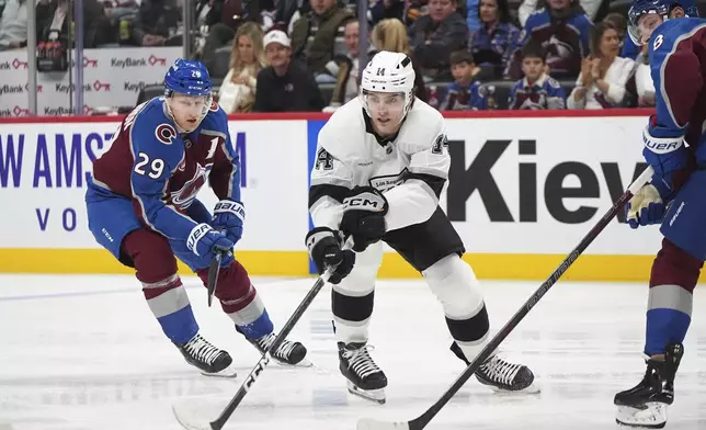 Los Angeles Kings right wing Alex Laferriere, center, collects the puck as Colorado Avalanche center Nathan MacKinnon, left, and defenseman Cale Makar cover in the second period of an NHL hockey game Wednesday, Nov. 13, 2024, in Denver. (AP Photo/David Zalubowski)