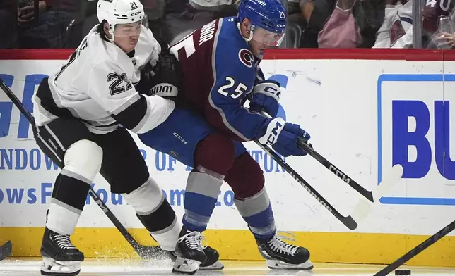 Los Angeles Kings defenseman Jordan Spence, left, fights for control of the puck with Colorado Avalanche right wing Logan O'Connor in the second period of an NHL hockey game Wednesday, Nov. 13, 2024, in Denver. (AP Photo/David Zalubowski)