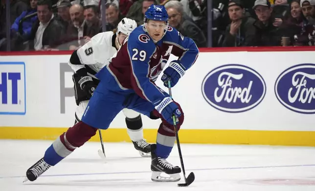 Colorado Avalanche center Nathan MacKinnon, front, collects the puck with Los Angeles Kings right wing Adrian Kempe in pursuit in the first period of an NHL hockey game Wednesday, Nov. 134, 2024, in Denver. (AP Photo/David Zalubowski)